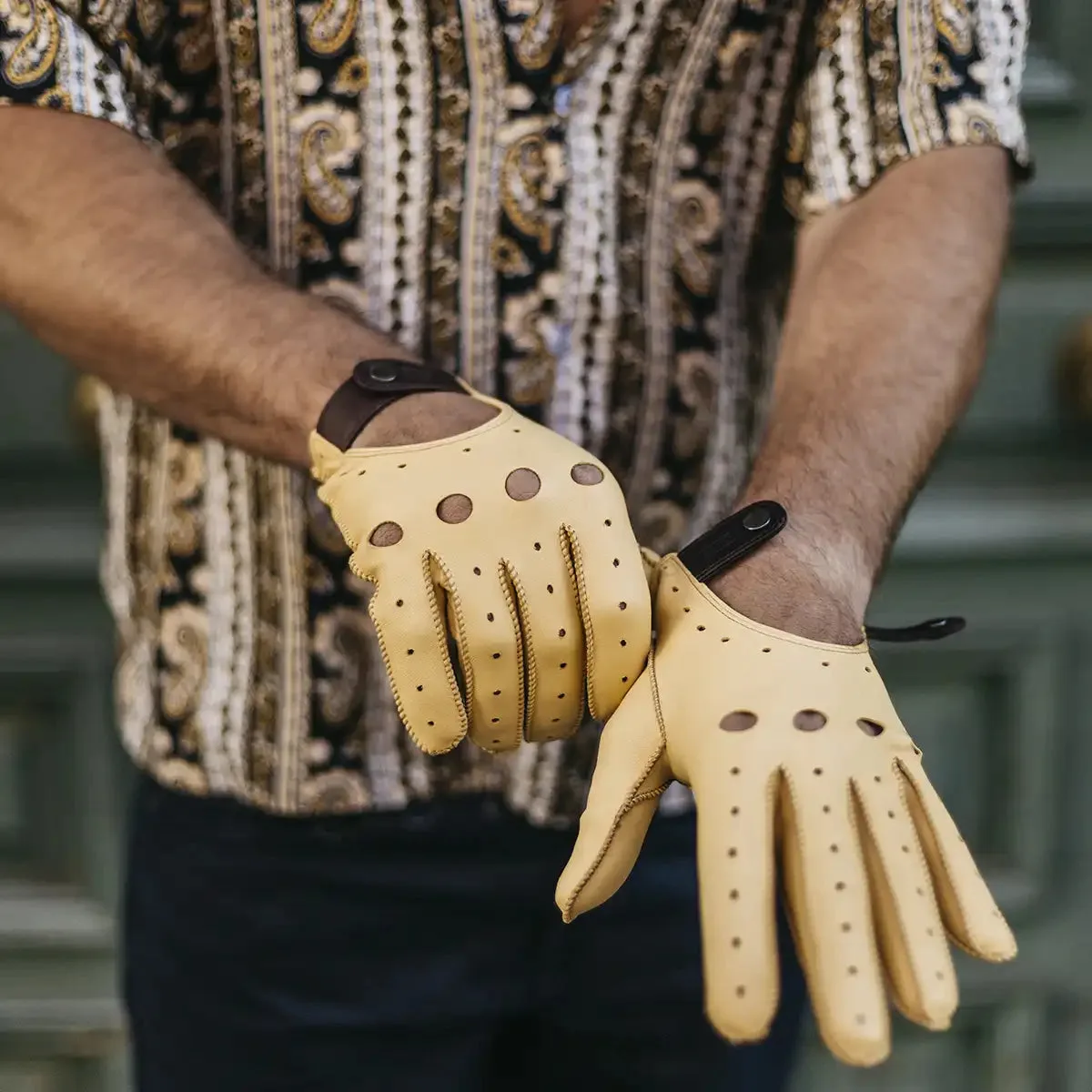 Yellow Café Leather driving gloves held against a steering wheel